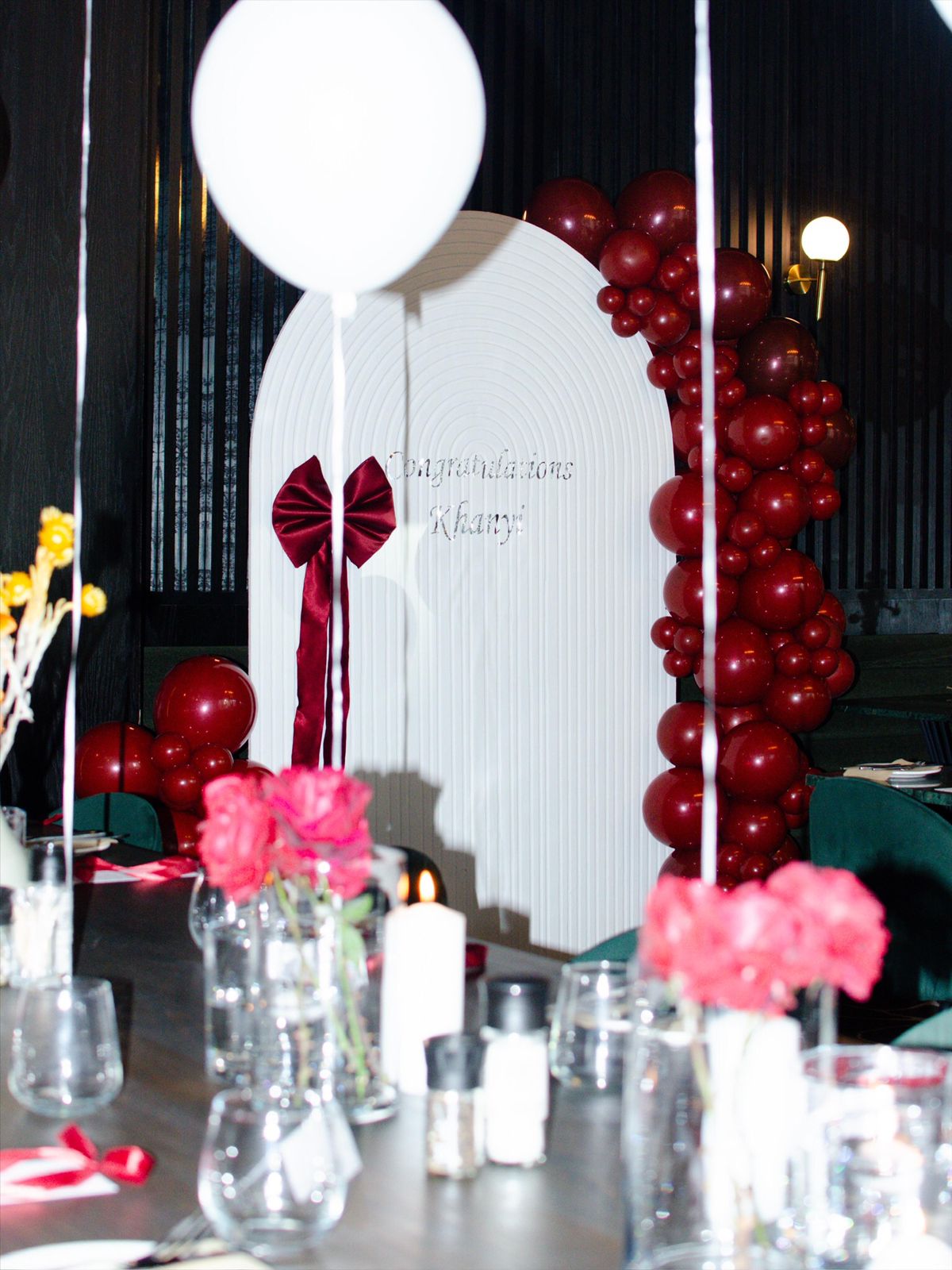 Burgundy balloon arch with congratulations backdrop